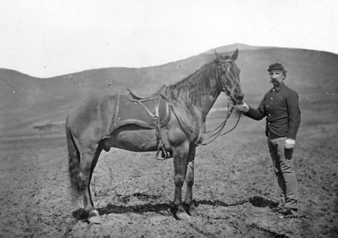 Pvt. Gustave Korn with Comanche the horse, rolling prairie in the background